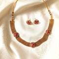 Gold necklace with pink floral designs on a white fabric background