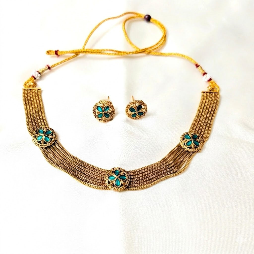 Gold necklace with green gemstones and matching earrings on a white background