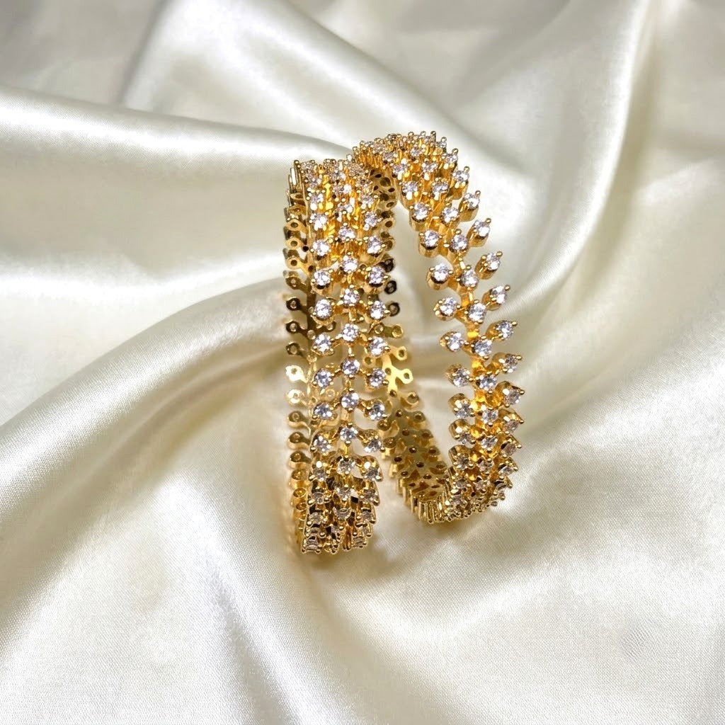 Gold Plated Diamond replica AD  grand bangle partywear covered with clear rhinestones, displayed on draped white satin fabric.