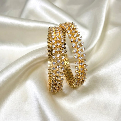 Gold Plated Diamond replica AD  grand bangle partywear covered with clear rhinestones, displayed on draped white satin fabric.