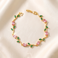 A gold bracelet featuring pink marquise-cut stones and green teardrop-cut stones.