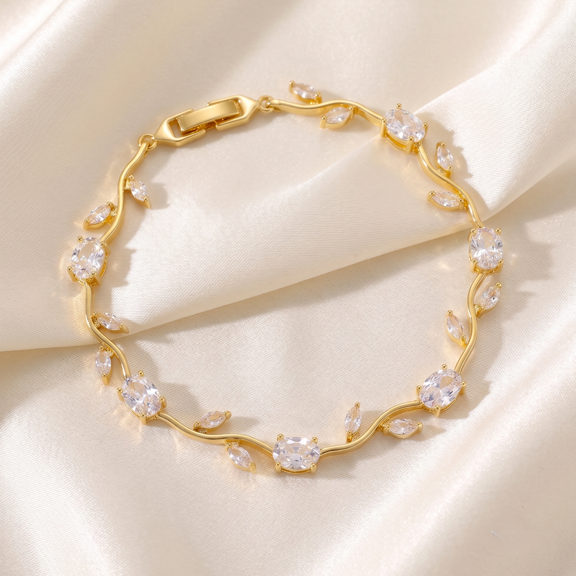 A gold vine-style bracelet adorned with clear teardrop and oval gemstones.