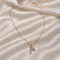 A delicate rose gold chain necklace with a small, leaf-shaped pendant paved with clear crystals, displayed on a draped cream satin fabric background.