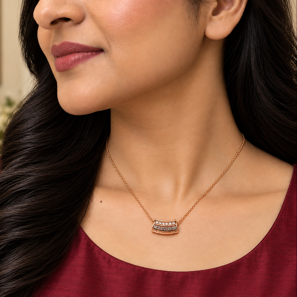 A close-up lifestyle shot of a woman wearing a rose gold necklace with a small rectangular pendant set with clear stones.
