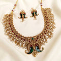 Gold-plated Indian jewelry set featuring a choker necklace and matching earrings with green enamel, red stone accents, and white pearl bead details, displayed on a cream satin fabric background.