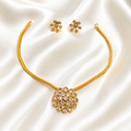 Gold necklace and matching stud earrings set with floral designs, displayed on a white satin fabric background.