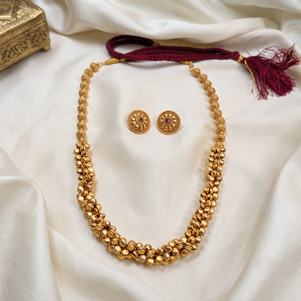 A gold-toned beaded ghungroo long necklace with a matching pair of stud earrings. Bharatnatyam necklace.