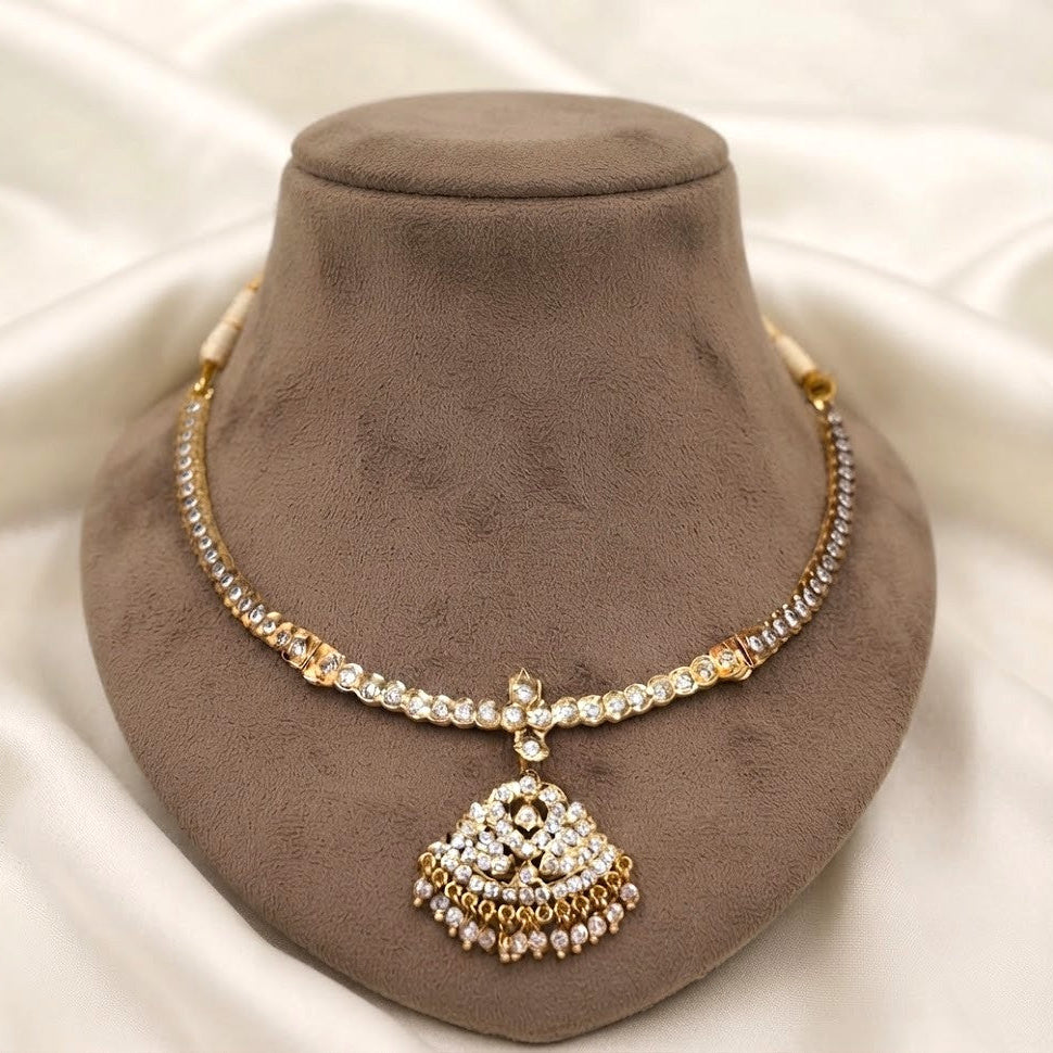  Embrace timeless elegance with this exquisite attigai necklace, crafted with antique gold plating and adorned with lustrous kemp stone details. 